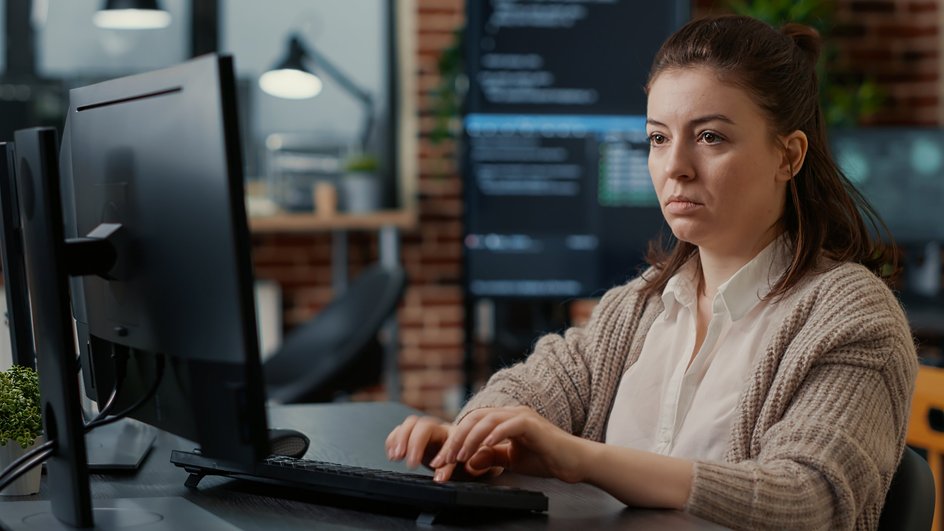 Девушка работает за компьютером и делает сноски в Word