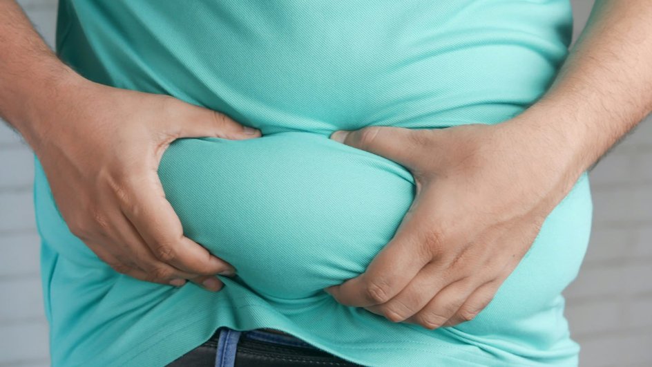 Человек держит живот, ожирение как потенциальная цель для микробных терапий