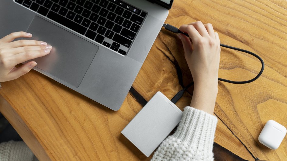 Женщина подключает SSD-диск к ноутбуку Женщина подключает SSD-диск к ноутбуку