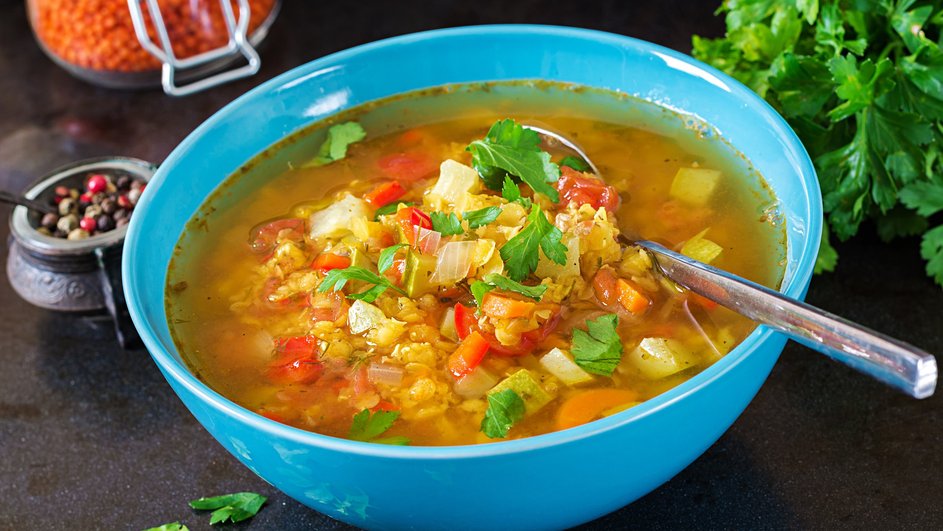 Тарелка супа с зеленым горошком, рисом и капустой стоит на столе