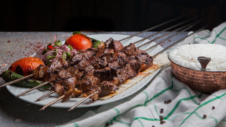 Шашлык на шампурах лежит на тарелке с овощами