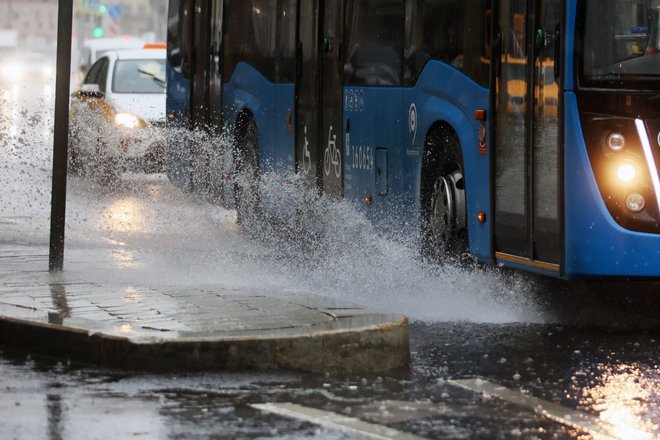 Автобус движется по проезжей части дороги во время дождя в центре Москвы