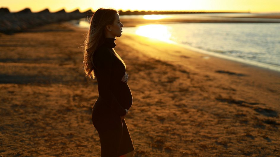беременная женщина позирует на берегу реки