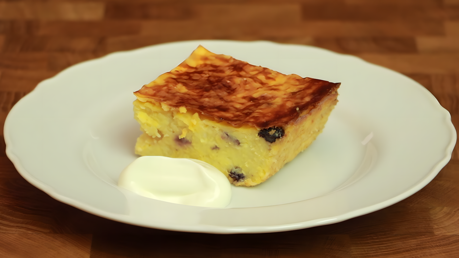 Кусочек пирога из пшенной каши лежит на тарелке рядом со сметаной