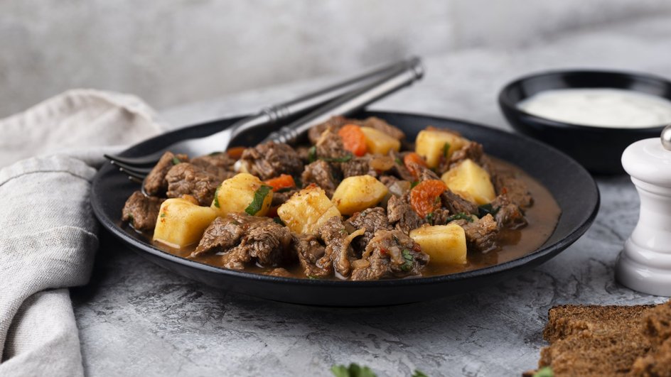 Тарелка запеченного картофеля с мясом стоит на столе Тарелка запеченного картофеля с мясом стоит на столе