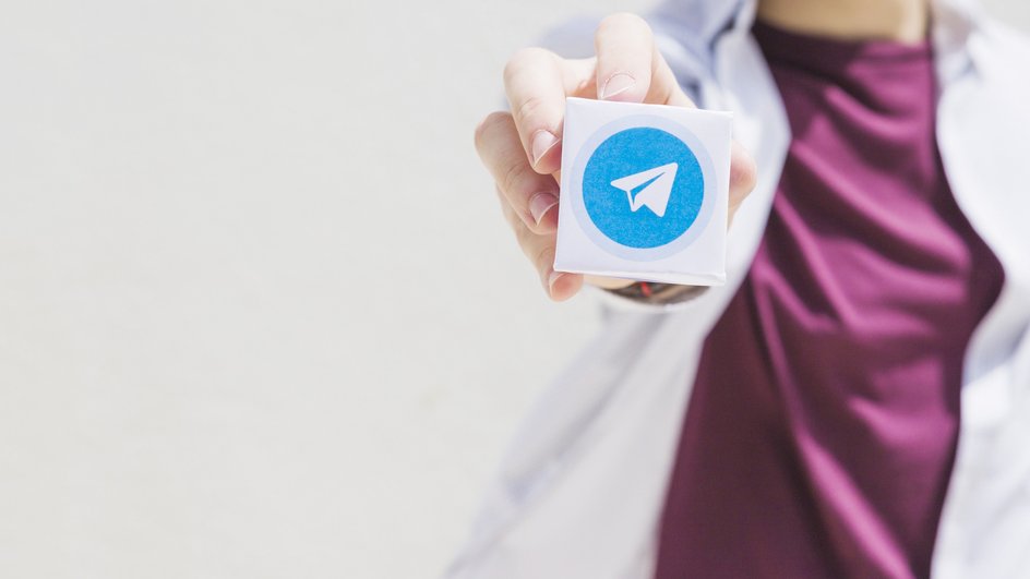 Логотип Telegram в руке