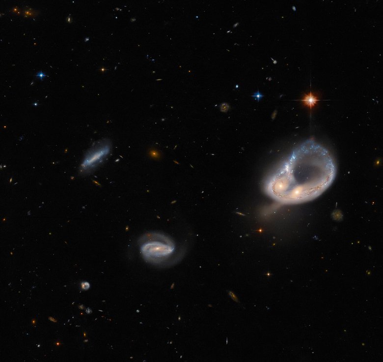 Две галактики (справа) образуют кольцо с выпуклостями. Слева видны две меньшие спиральные галактики, а также несколько звезд. Фото: NASA / ESA / Hubble 
