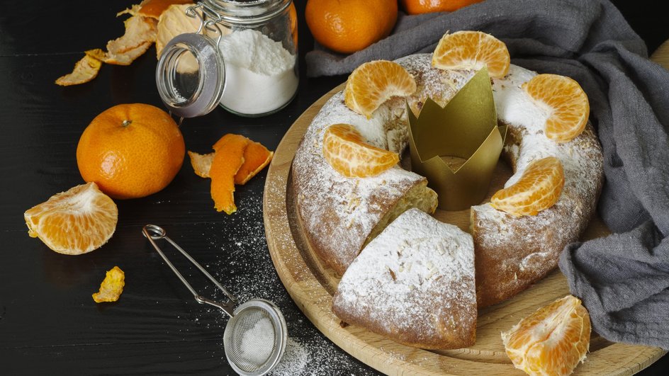Постный пирог с яблоками, морковью и мандарином лежит на подставке рядом с ингредиентами
