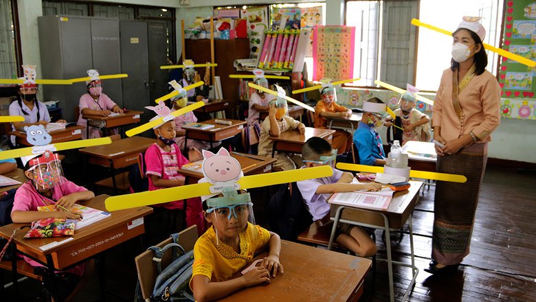 Учитель и школьники в специальных шапках для социальной дистанции в школе Пан Па Муад в Чиангмае, к северу от Таиланда