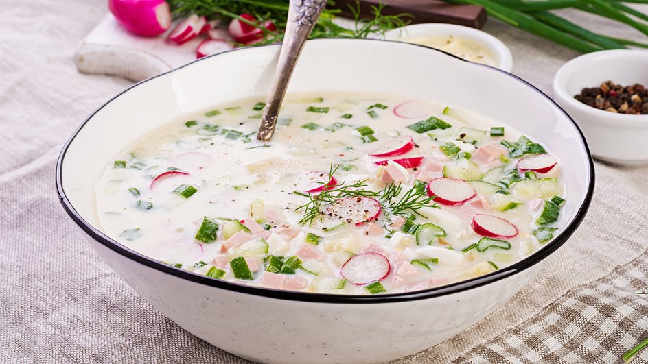 Миска окрошки с ложкой стоит на столе
