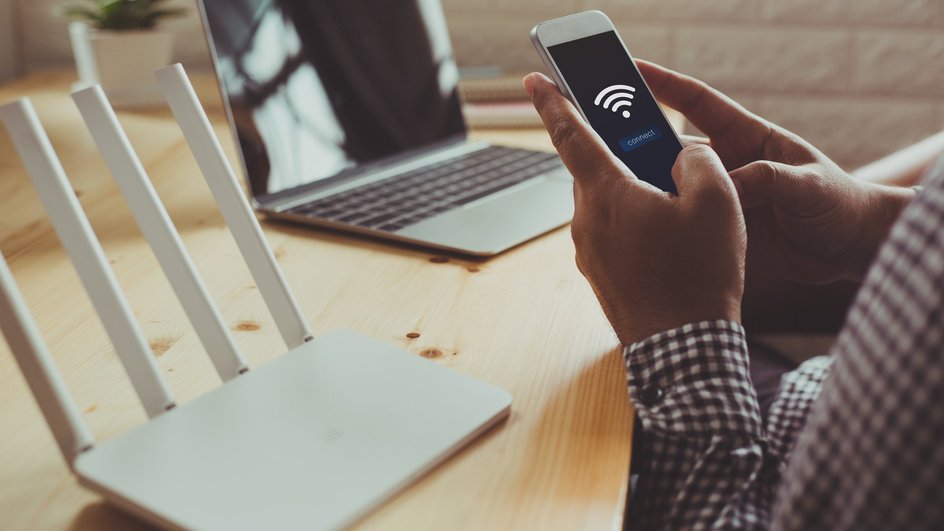 Мужчина пытается подключиться к Wi-Fi роутеру через телефон