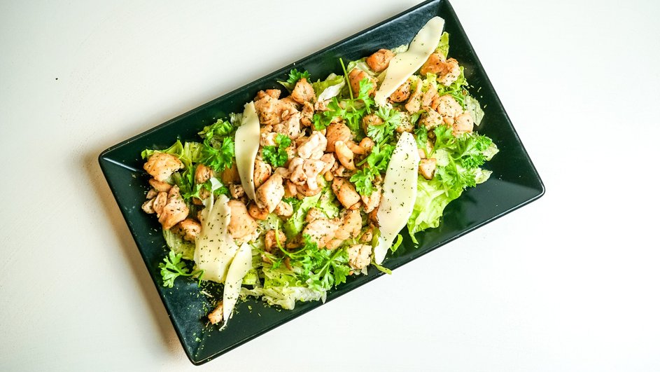 Теплый салат с куриным мясом лежит в большой тарелке Теплый салат с куриным мясом лежит в большой тарелке