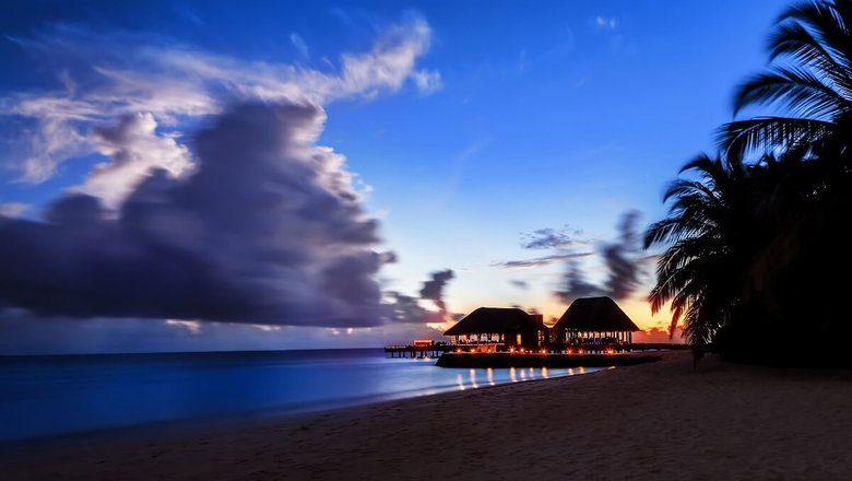 Закат на пляже Ваадху на Мальдивах и уютные домики отелей.