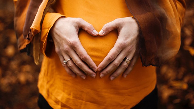 Беременная женщина обнимает живот