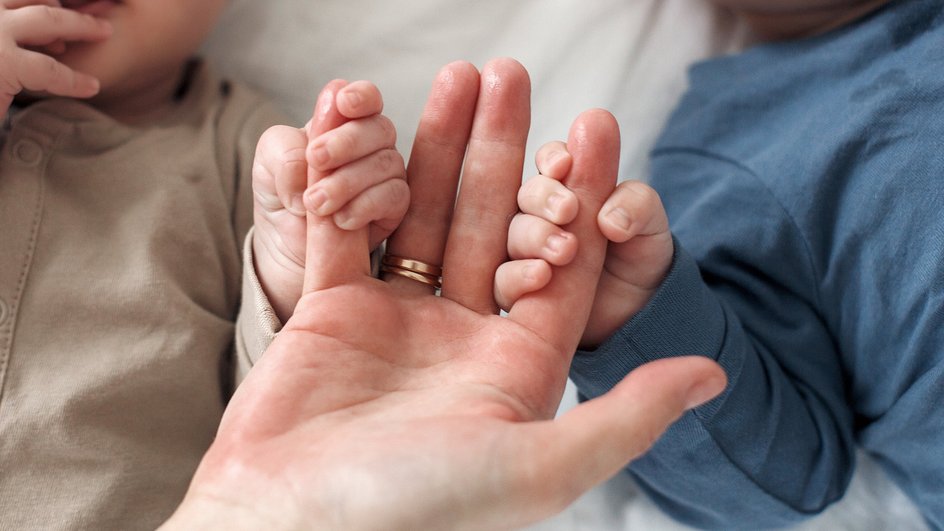 новорожденные двойняшки держат маму за пальцы