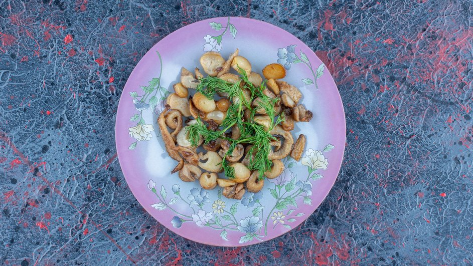 Маринованные маслята с зеленью на тарелке Маринованные маслята с зеленью на тарелке