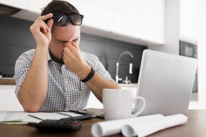 У мужчины устали и покраснели глаза от работы за компьютером У мужчины устали и покраснели глаза от работы за компьютером