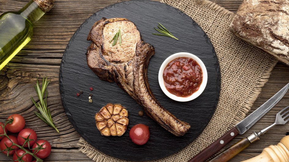 Кусок мяса лежит на подставке рядом с соусом барбекю