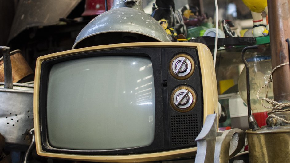 Старый телевизор и металлический хлам на стеллажах 