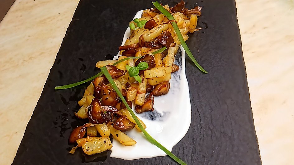 Картофель с жареными маслятами, зеленым луком и сметаной на сервировочной тарелке Картофель с жареными маслятами, зеленым луком и сметаной на сервировочной тарелке