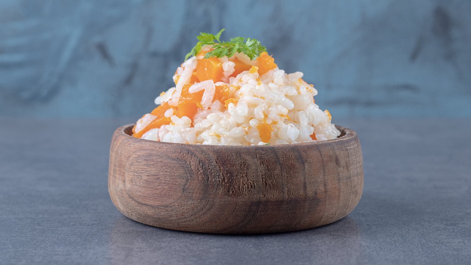 Тарелка постной рисовой каши с курагой и апельсином стоит на столе