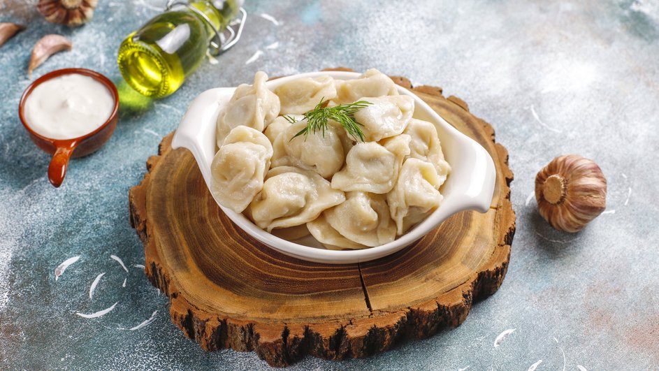 Пельмени с индейкой и сыром, украшенные зеленью Пельмени с индейкой и сыром, украшенные зеленью