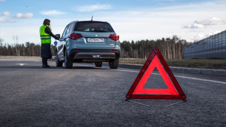 Девушка в жилете на трассе, знак аварийной остановки Девушка в жилете на трассе, знак аварийной остановки
