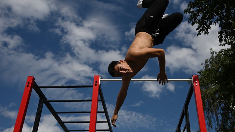 Спортсмен исполняет трюк на турнике.