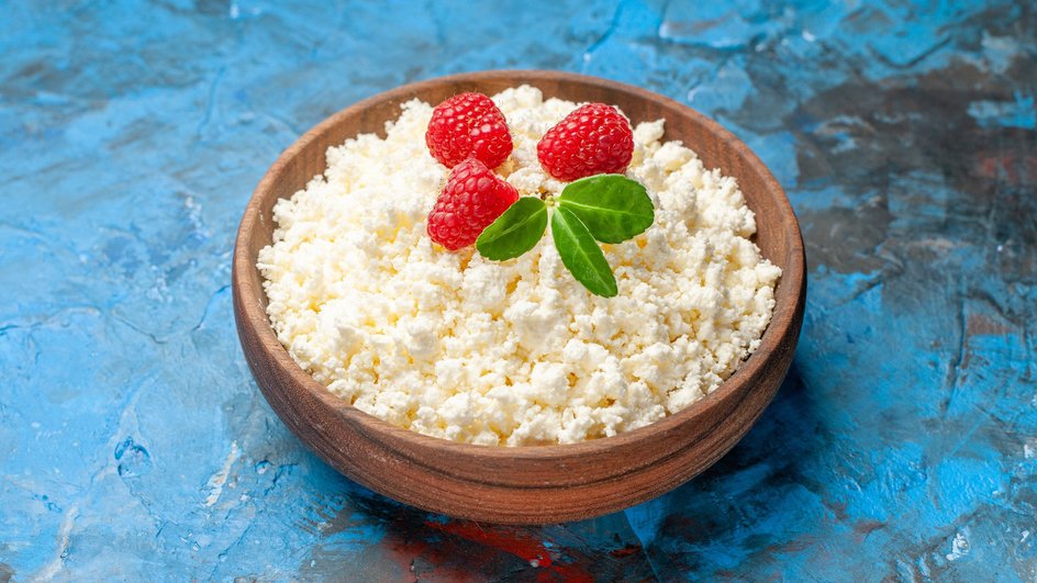 Обезжиренный творог со свежим вкусом, запахом и цветом в деревянной тарелке на синем столе Обезжиренный творог со свежим вкусом, запахом и цветом в деревянной тарелке на синем столе