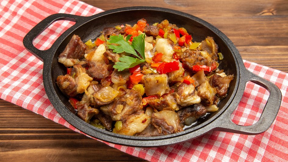 Рагу из картошки со свининой, приготовленное на сковород, лежит на тарелке