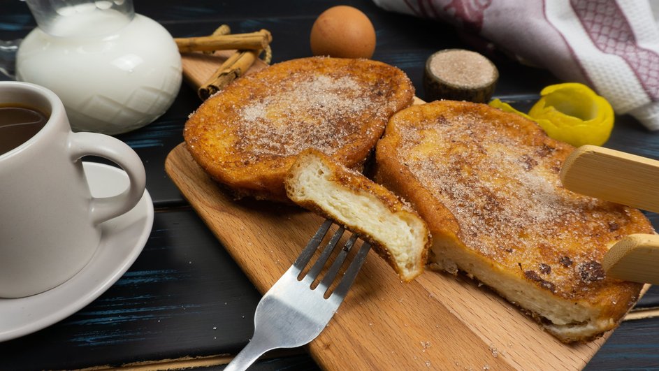 Сладкие гренки с яйцом и сахаром на деревянной доске 