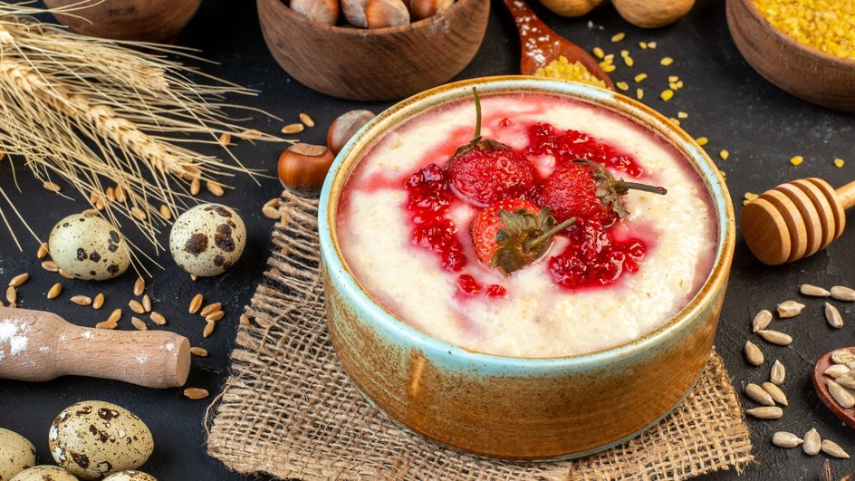 Тарелка гурьевской каши с клубникой стоит на столе рядом с перепелиными яйцами Тарелка гурьевской каши с клубникой стоит на столе рядом с перепелиными яйцами