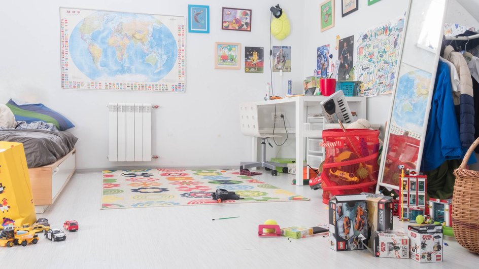 Светлая детская комната с картой мира на стене, детскими рисунками, письменным столом и кравитью