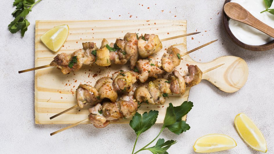 Куриный шашлык лежит на доске рядом с долькой лимона Куриный шашлык лежит на доске рядом с долькой лимона