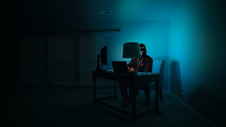 Мошенник в маске сидит за компьютером