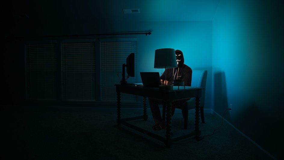 Человек сидит за компьютером с закрытым лицом
