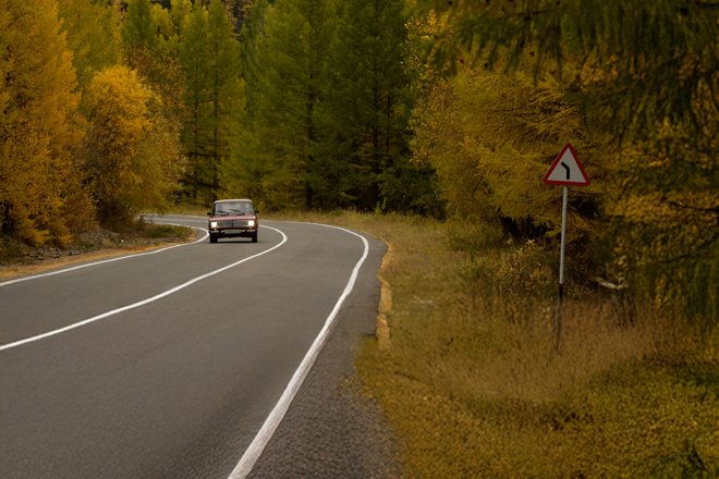 Автомобильная дорога в горах в Республике Тыва с дорожным знаком "Опасный поворот" Автомобильная дорога в горах в Республике Тыва с дорожным знаком "Опасный поворот"