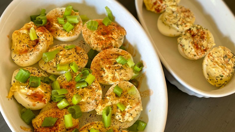 Фаршированные яйца с чесноком и сыром, украшенные зеленью, лежат на тарелке