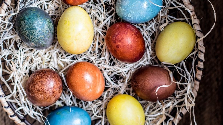 Разноцветные пасхальные яйца в плетеной корзине