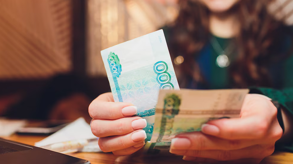 Девушка-Близнецы держит в руках денежные купюры Девушка-Близнецы держит в руках денежные купюры
