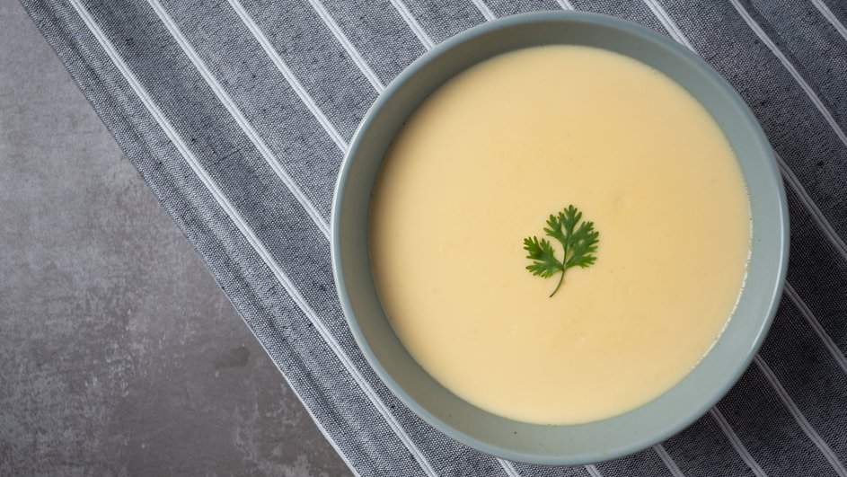 Тарелка супа-пюре с плавленым сыром, картофелем и курицей стоит на столе