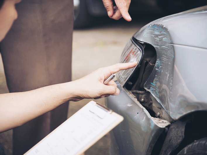 Девушка трогает разбитую фару в автомобильной аварии Девушка трогает разбитую фару в автомобильной аварии