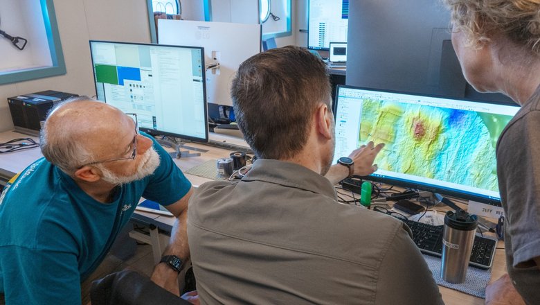 Ученые Дэвид Кэресс, Дженнифер Падуан и Джефф Бисон рассматривают карту геологических особенностей морского дна. Фото: Schmidt Ocean Institute