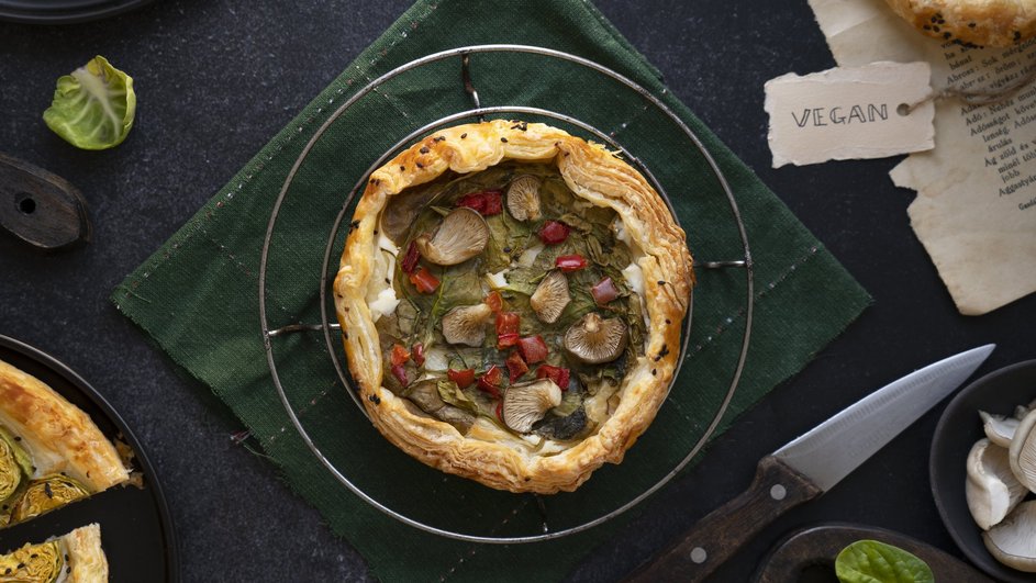 Пирог с начинкой из маслят, шпината и болгарского перца, поданный на черной тарелке