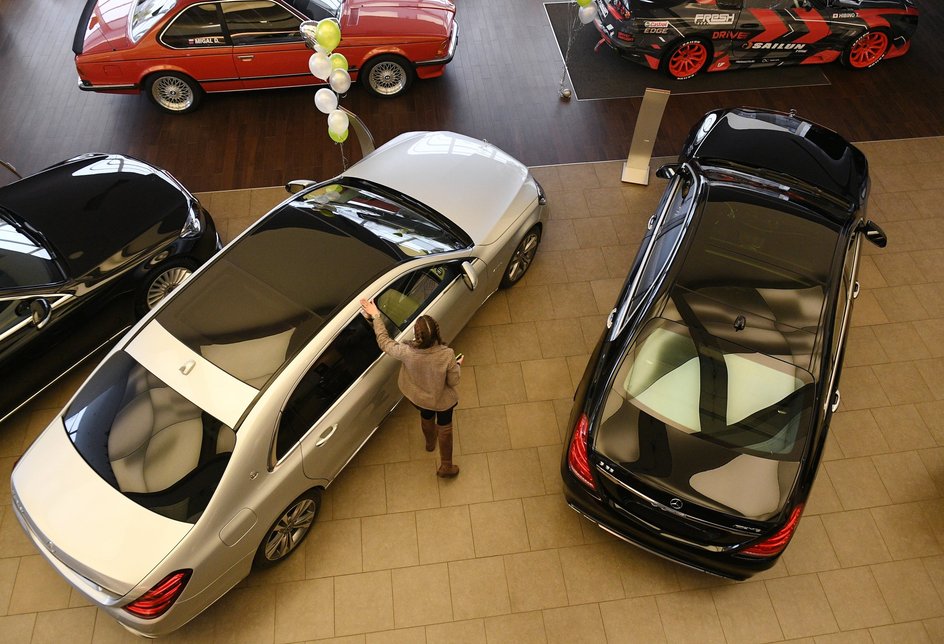 Менеджер демонстрирует покупателям автомобиль в автосалоне по продаже подержанных авто Fresh Auto в Москве.