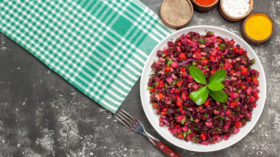 Постный салат с кукурузой и свеклой лежит на тарелке рядом со специями