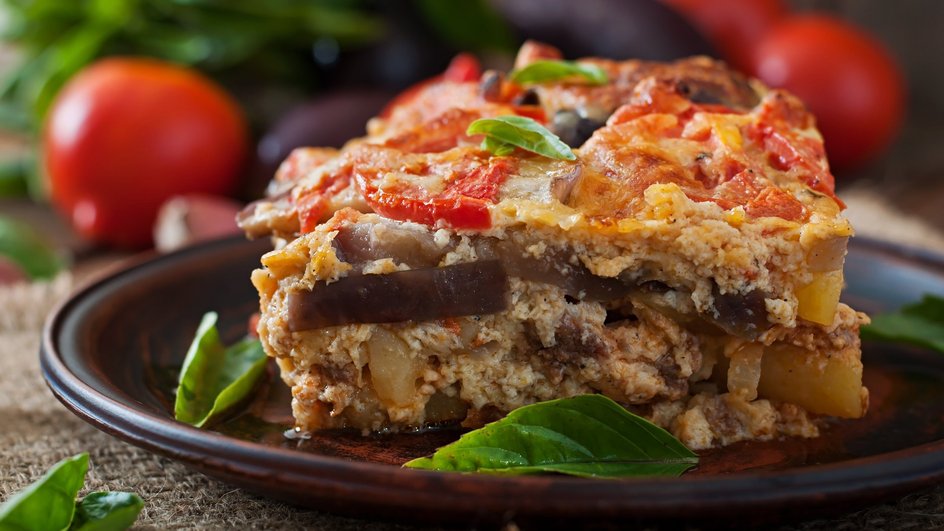 Кусочек классической мусаки с баклажанами, фаршем и картофелем крупным планом Кусочек классической мусаки с баклажанами, фаршем и картофелем крупным планом