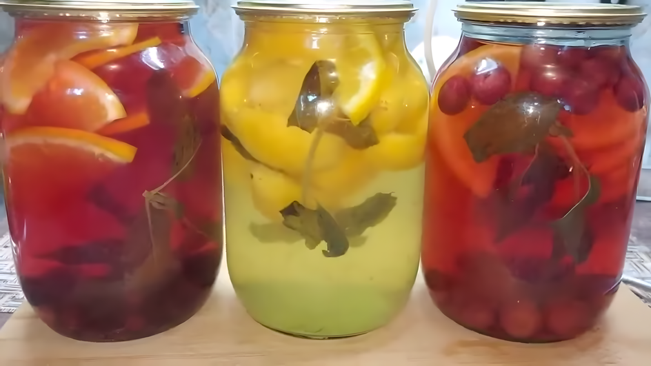 Банки компота из красных апельсинов с мятой стоят на столе близко друг к другу