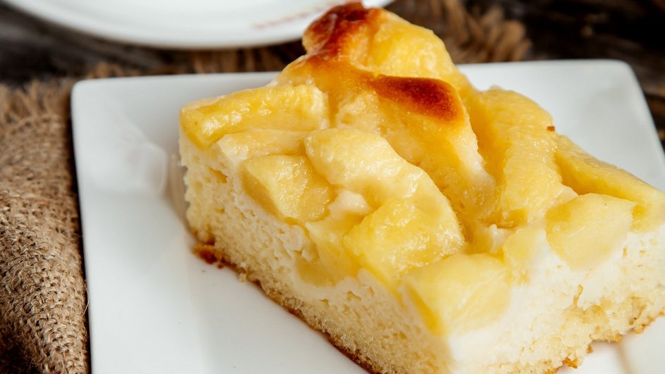 Кусочек шарлотки с ананасом и кокосом лежит на тарелке