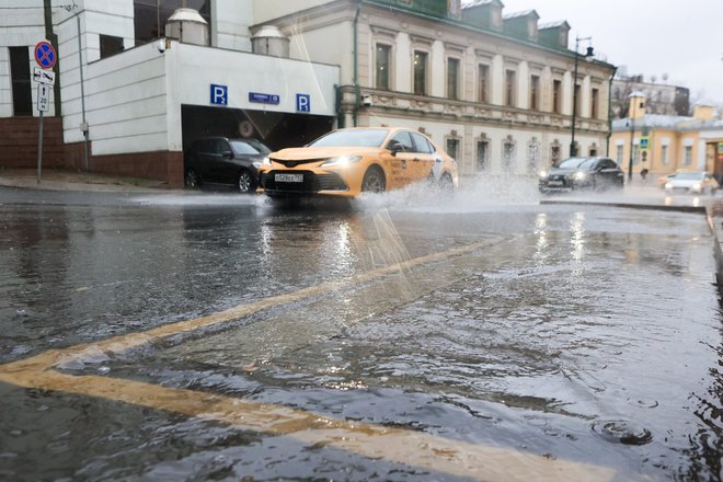 Такси проезжает по лужам в Москве